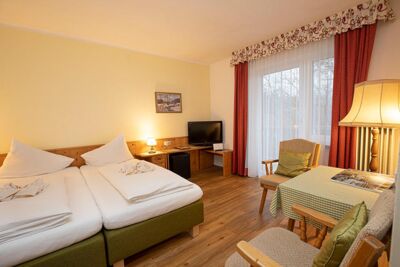 Ein Doppelbett und zwei Stühle mit einem Tisch befinden sich im Hotelzimmer des Landhotel Agathawirt