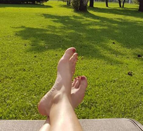 A woman puts her feet up on the lounger in the garden