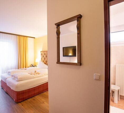 Ein Hotelzimmer im Hotel Agathawirt mit Doppelbett, einer Balkontür und einem Badezimmer