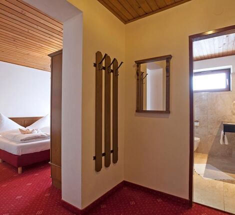 Ein kleiner Vorraum der ins Schlafzimmer mit einem Doppelbett und in ein Badezimmer führt