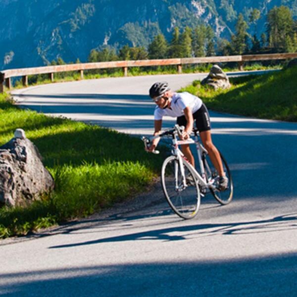 Ein Rennradfahrer fährt mit seinem Fahrrad eine Bergstraße hinunter